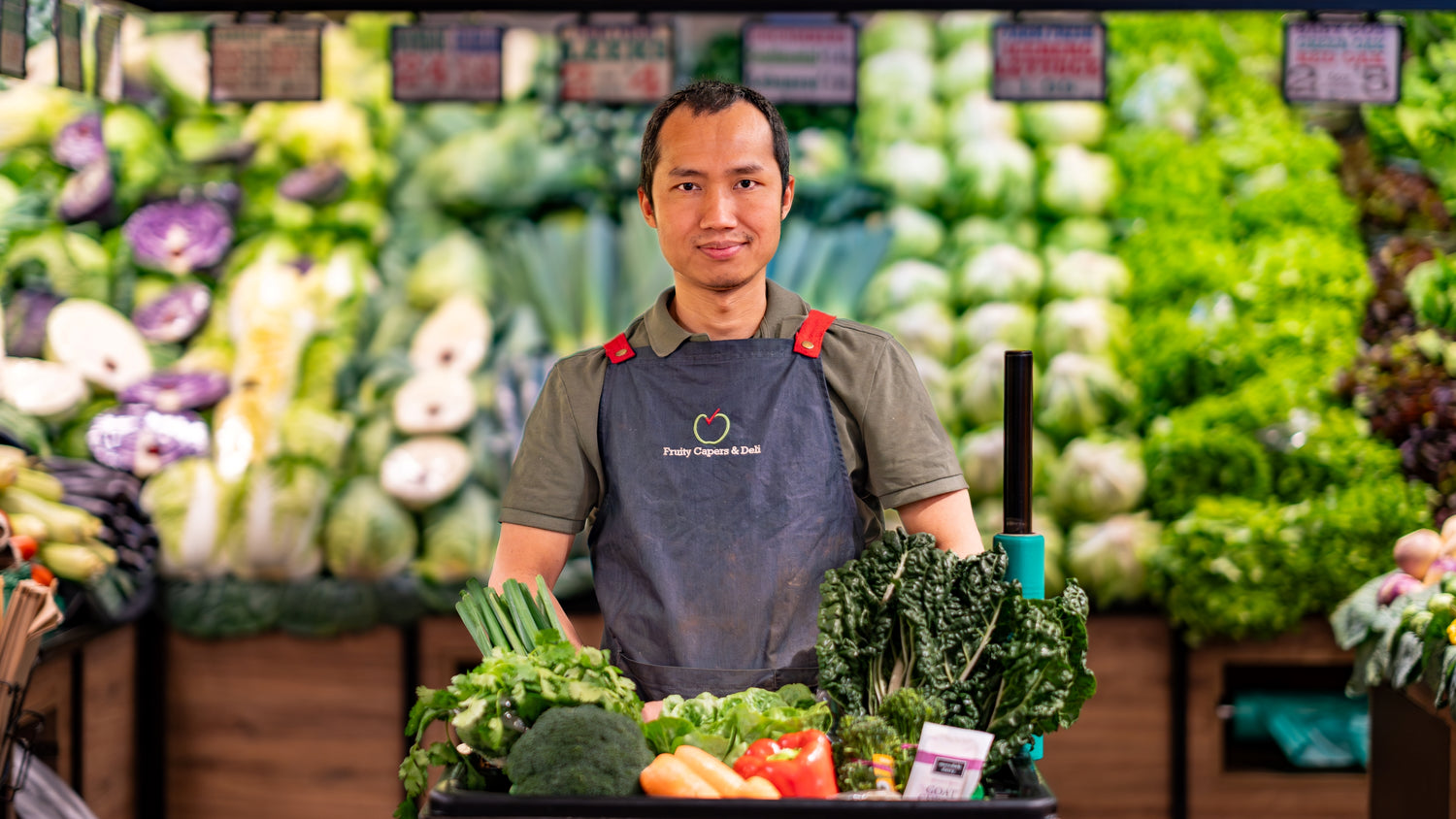 Fruity Capers & Deli team member with fresh greens and vegetables